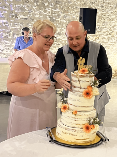 Couple heureux coupant un gâteau de mariage à étages décoré de fleurs lors d'une réception.